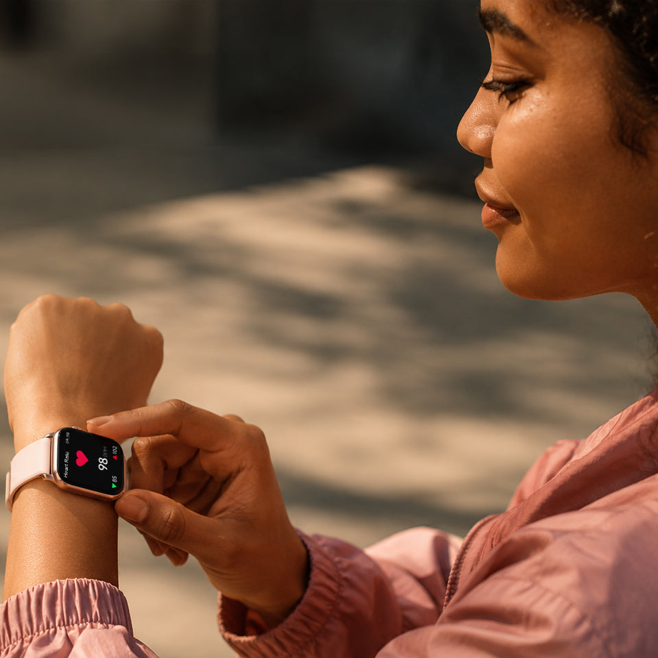 Une femme touche l'écran de sa montre connectée rose