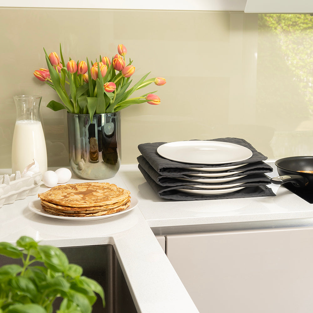 Bordenwarmer met borden in een lichte keuken naast tulpen en pannenkoeken