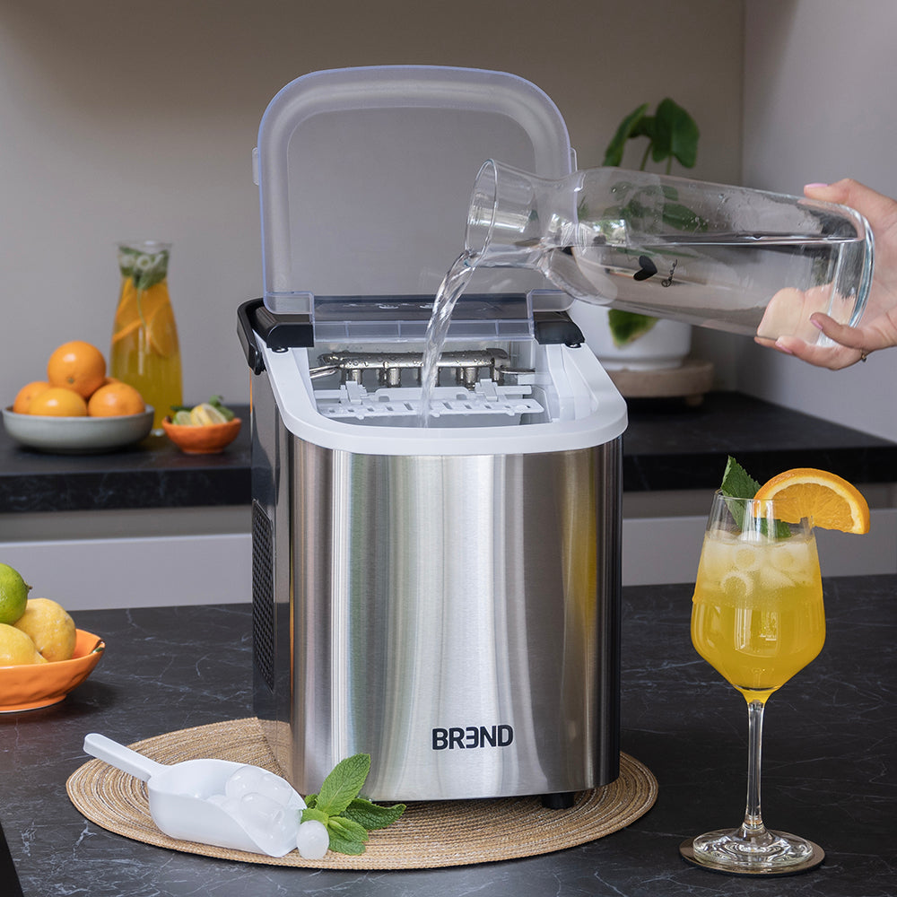 Water wordt uit een karaf in het reservoir van de roestvrijstalen ijsblokjesmachine geschonken