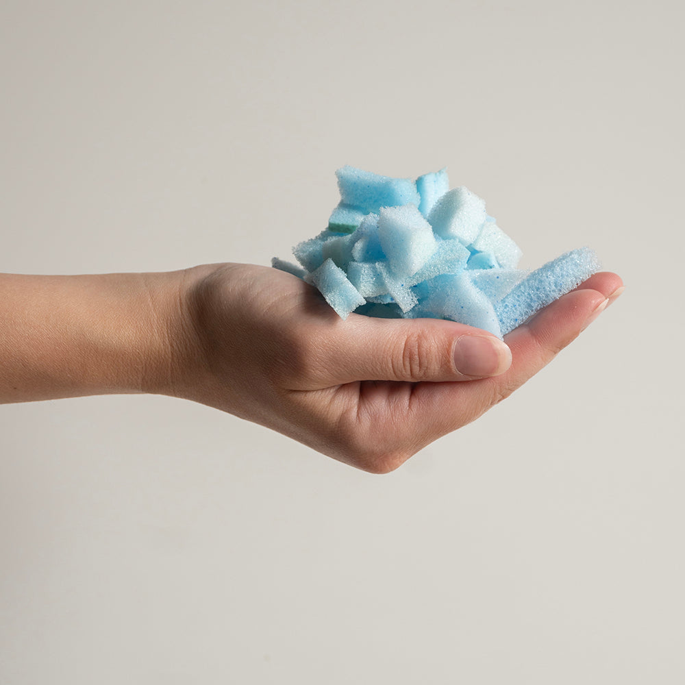 Geopende hand met een handvol blauwe schuimvlokken uit het hoofdkussen