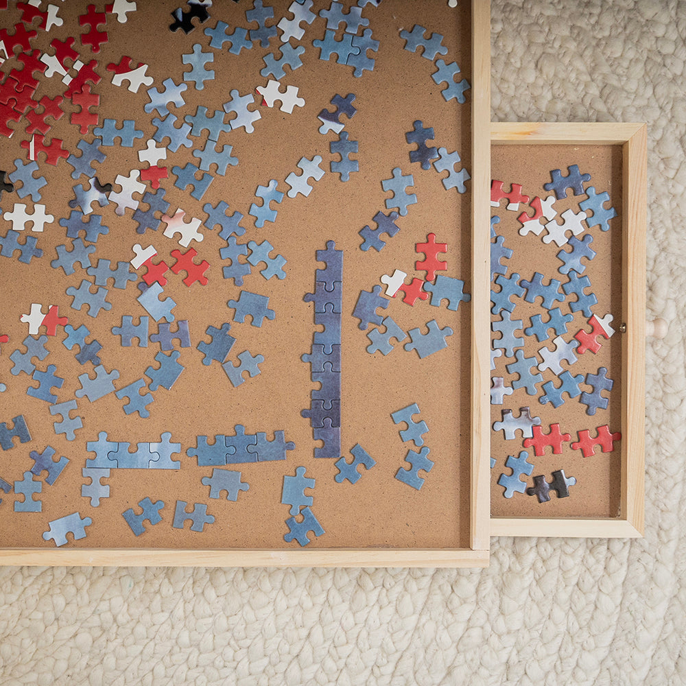 Bovenaanzicht van de puzzelplaat met een uitgeschoven lade vol puzzelstukjes