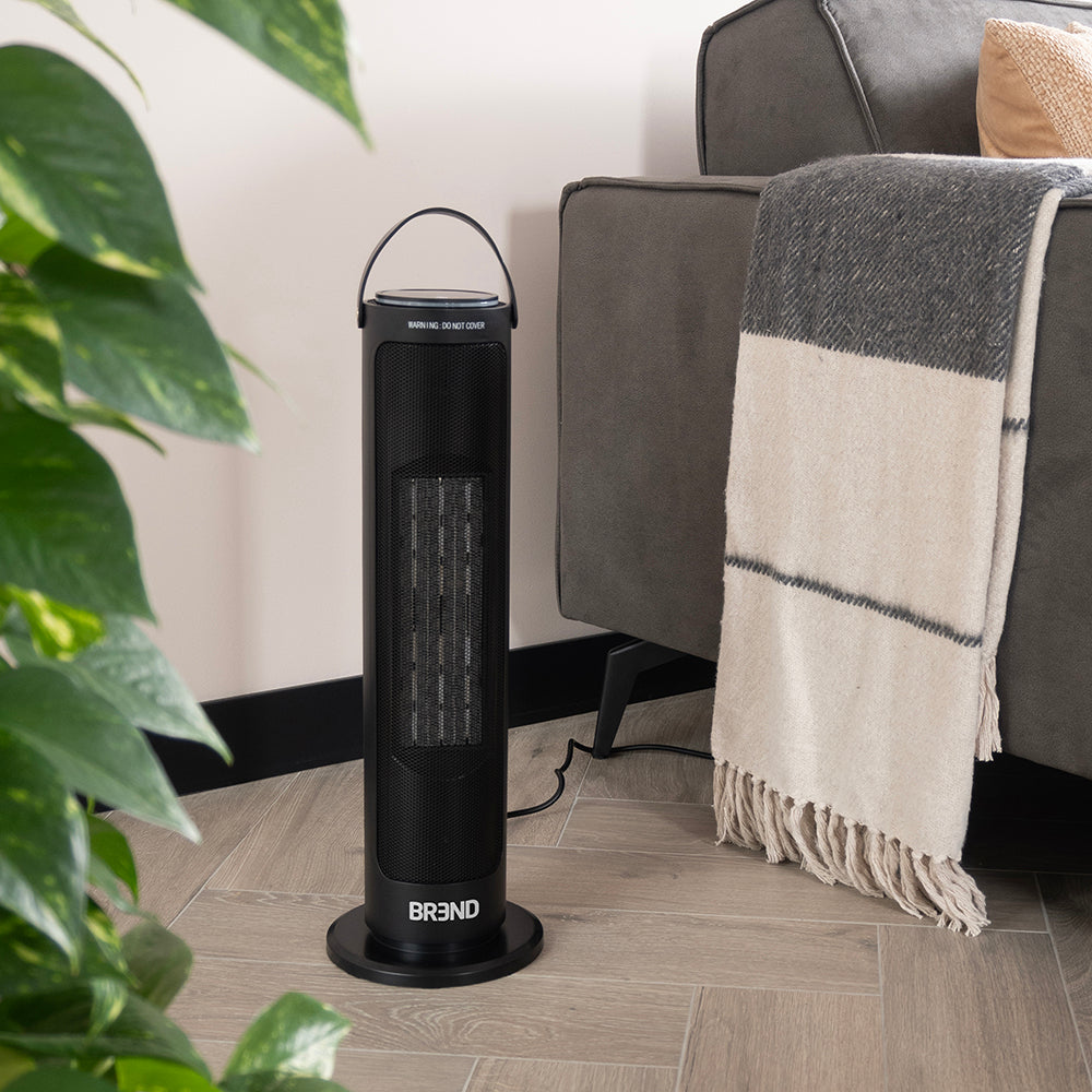 Torenkachel ECO staat op een houten vloer naast de bank, tussen de planten