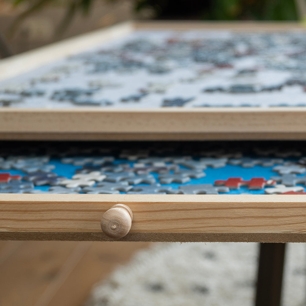 Close-up van een lade met blauw vilt en houten knop vol puzzelstukjes