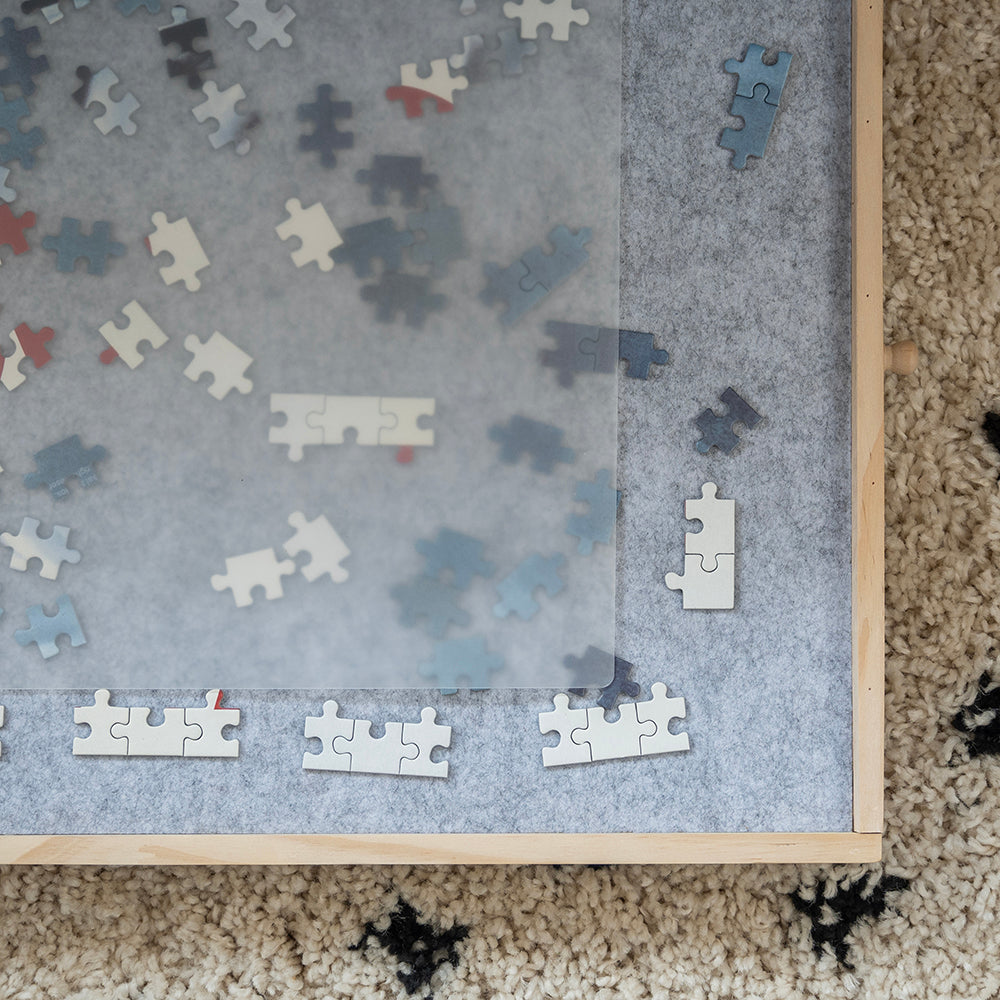 Close-up van de hoek van de puzzelplaat met de transparante afdekplaat over de puzzelstukjes