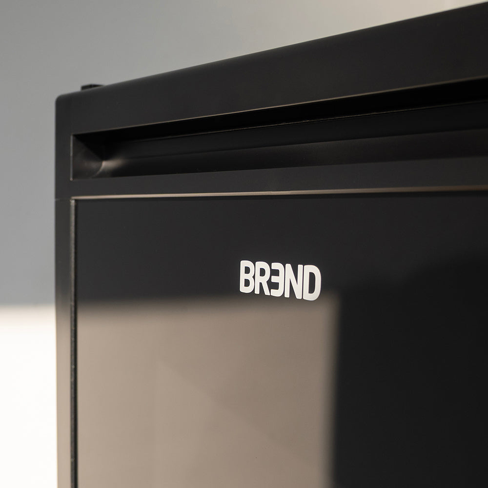 Close-up van het BREND-logo en de greeplijst op de deur van de mini koelkast