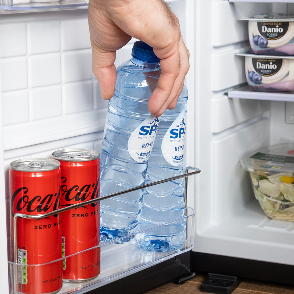 Hand pakt een fles water uit het deurvak van de mini koelkast