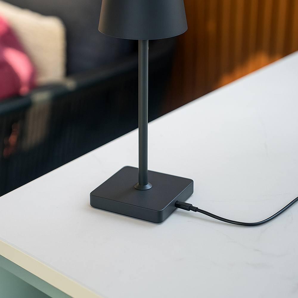 Voet van de zwarte tafellamp met aangesloten USB-oplaadkabel