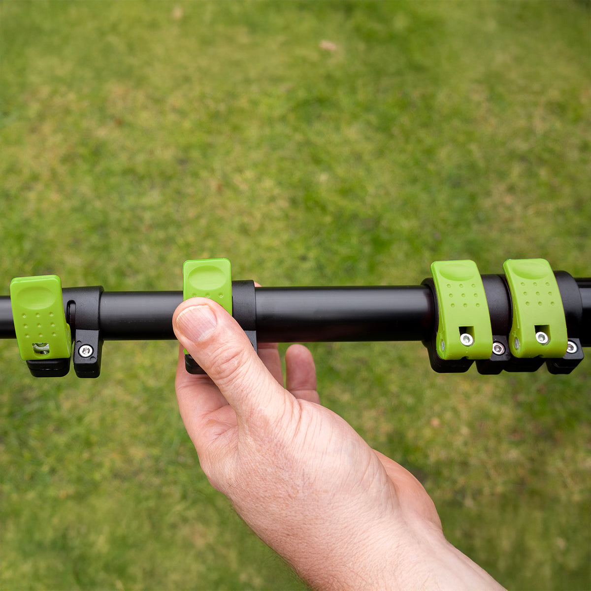 Une main ouvre un collier de serrage vert pour déployer le manche télescopique