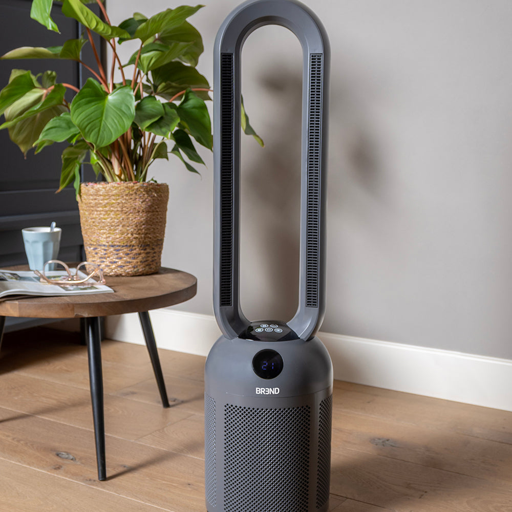 Grijze bladloze ventilatorkachel in een woonkamer naast een bijzettafel met plant