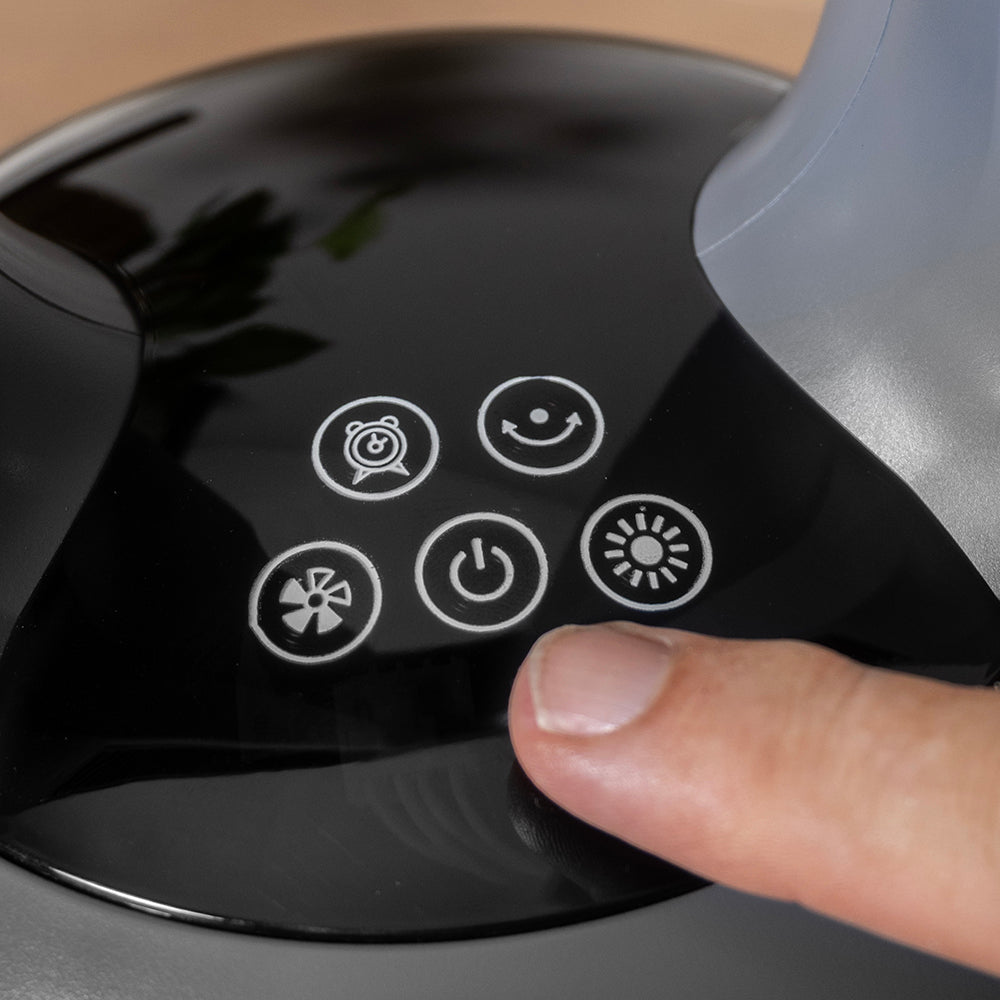 Vinger drukt op de aan-uitknop van het aanraakpaneel van de ventilatorkachel