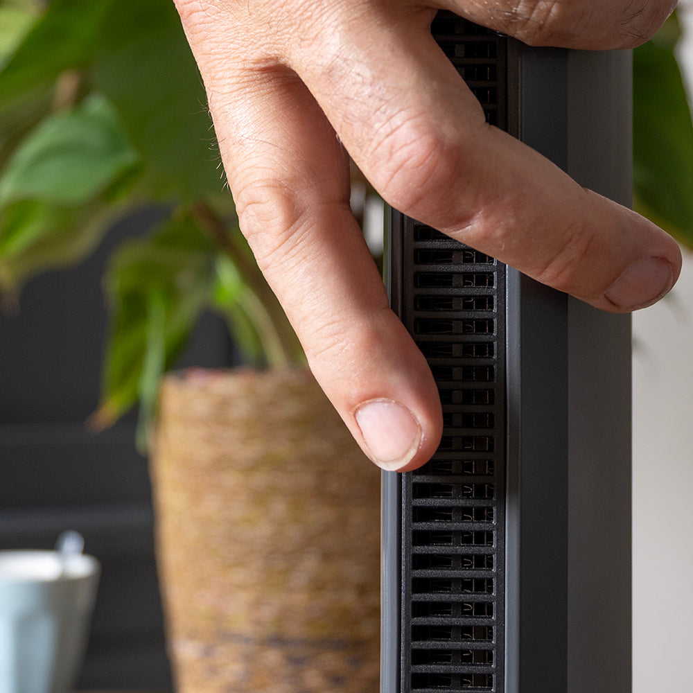 Hand voelt de luchtstroom bij het uitblaasrooster van de bladloze ventilatorkachel
