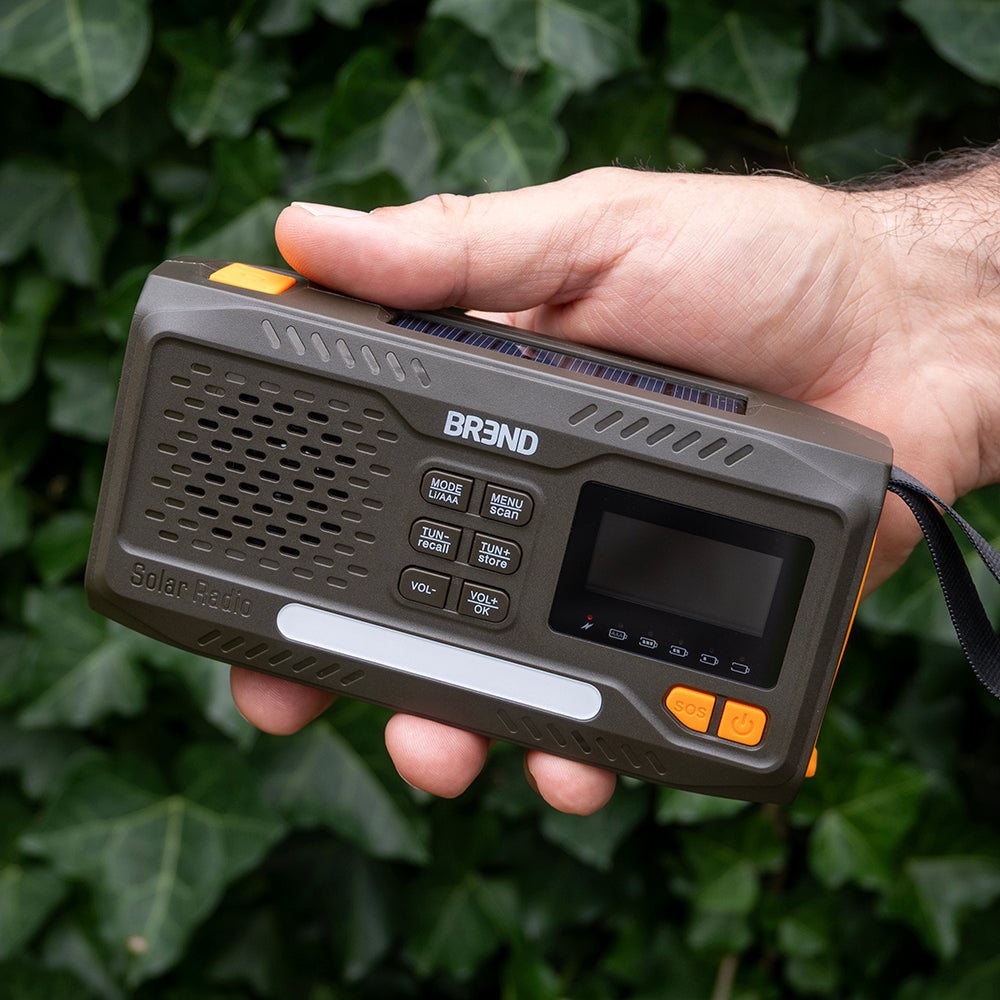 Hand houdt de compacte noodradio vast voor een klimophaag