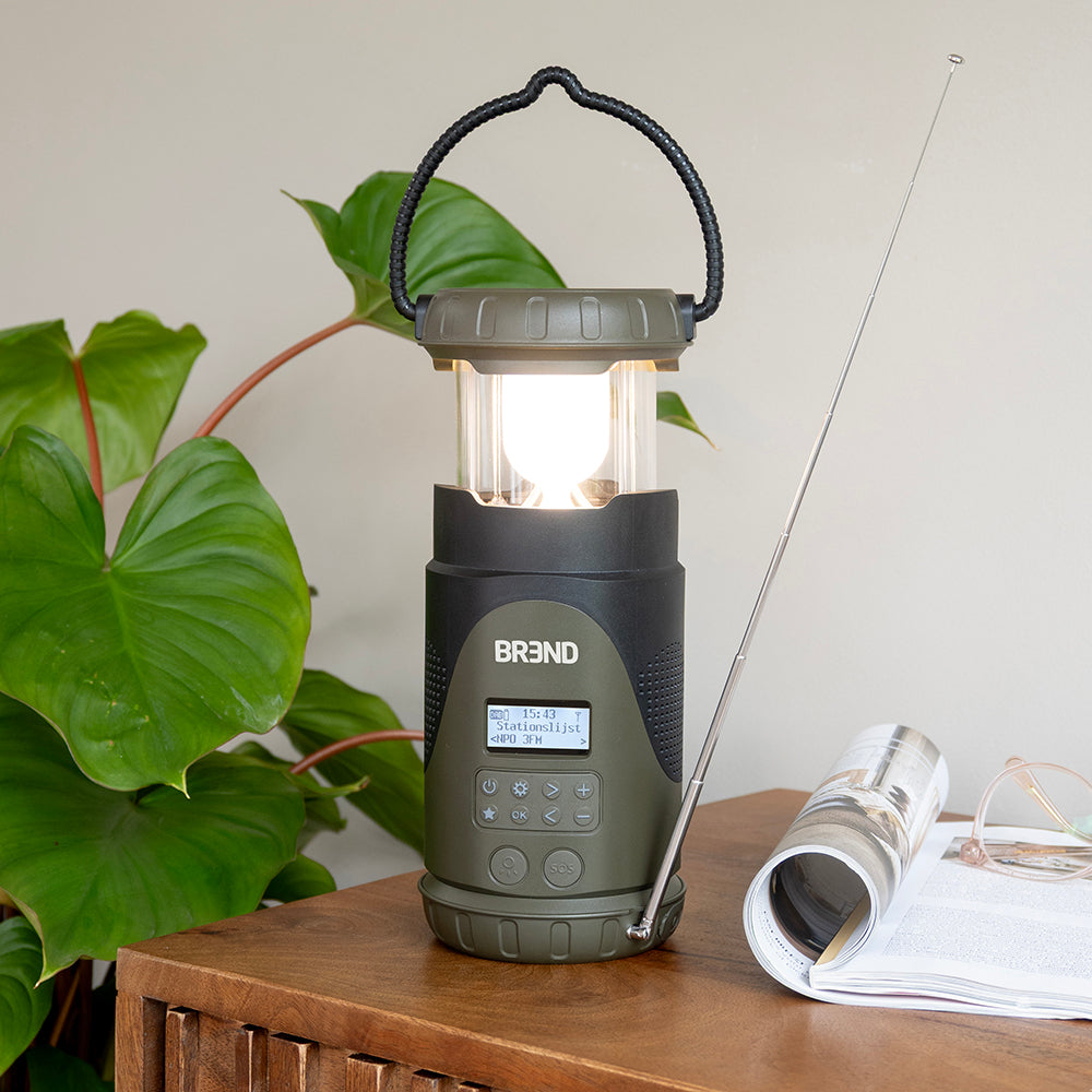 Noodradio met uitgeschoven brandende lantaarn en antenne op een bijzettafel naast een tijdschrift