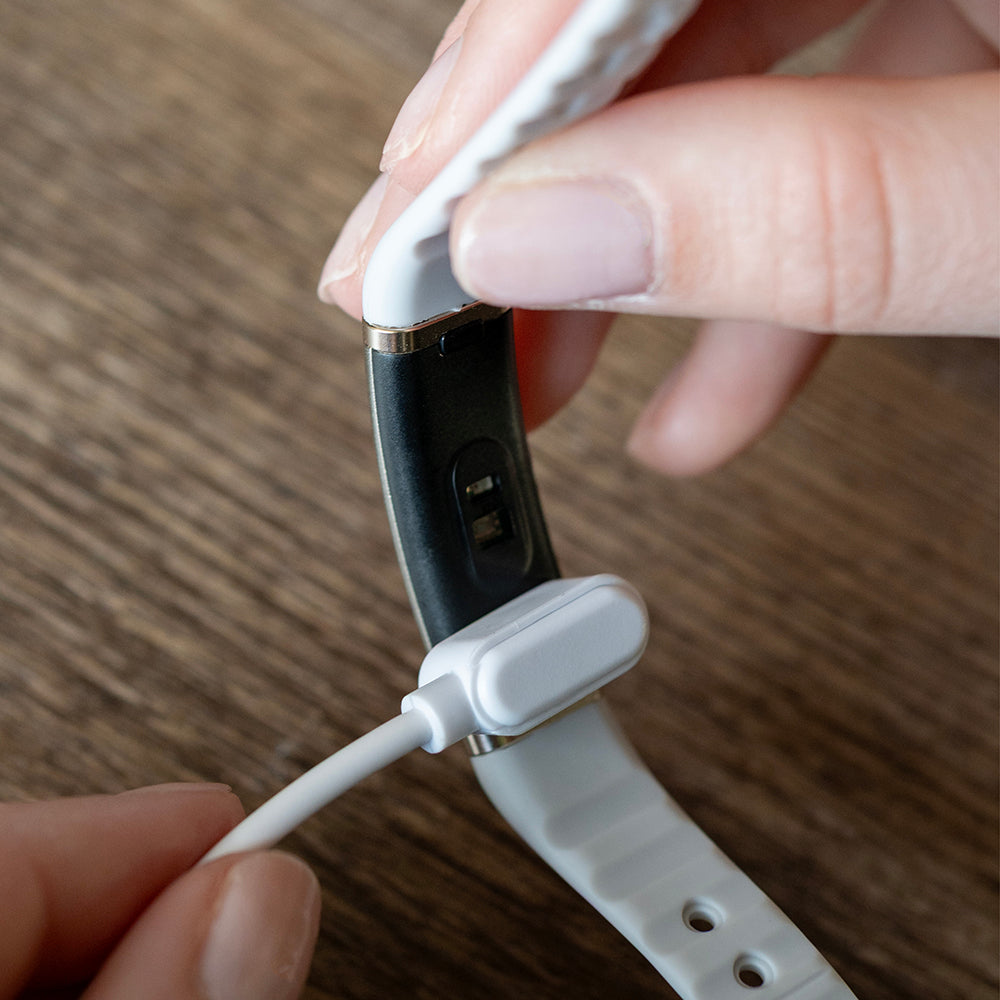 Magnetische oplaadkabel wordt op de achterkant van de activity tracker geklikt