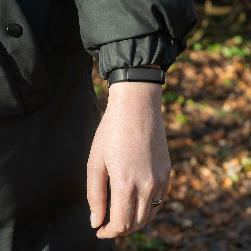 Zwarte activity tracker om de pols tijdens een wandeling in het bos
