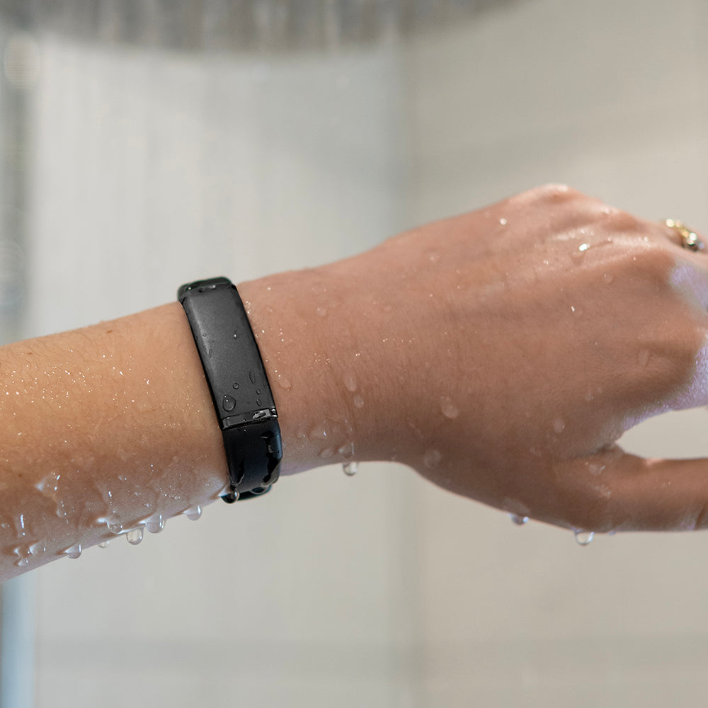 Zwarte activity tracker om een natte pols onder stromend water