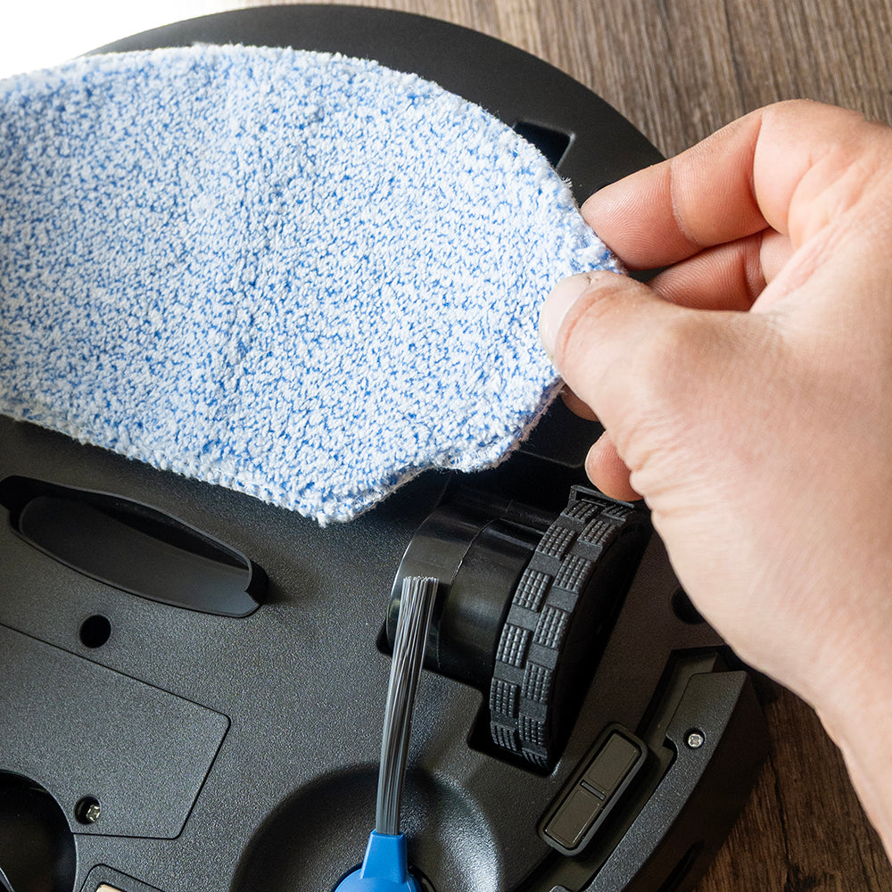 Hand bevestigt de blauwe dweildoek aan de onderkant van de robotstofzuiger