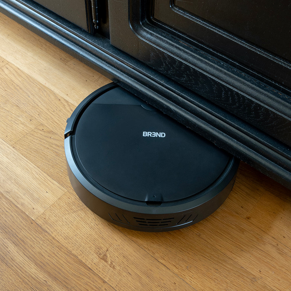 Robotstofzuiger rijdt onder een zwarte kast door