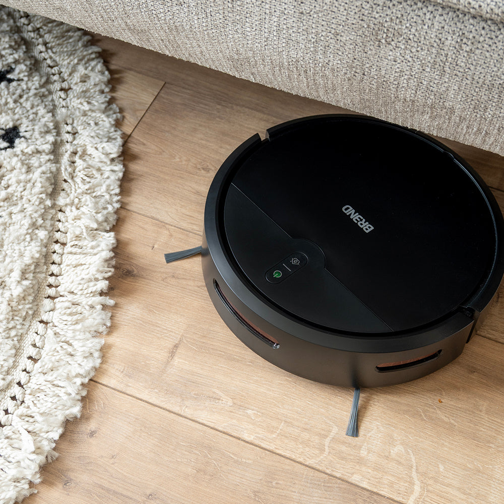 Robotstofzuiger zuigt de houten vloer langs de rand van een vloerkleed