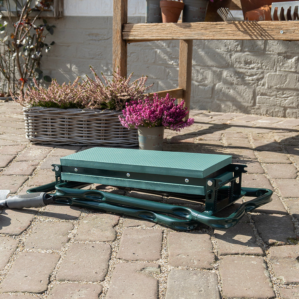 Ingeklapte tuinkruk ligt plat op een terras voor een plantenbak met heide