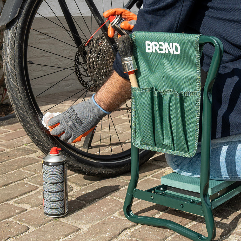 Man knielt op de tuinkruk en maakt een fietswiel schoon