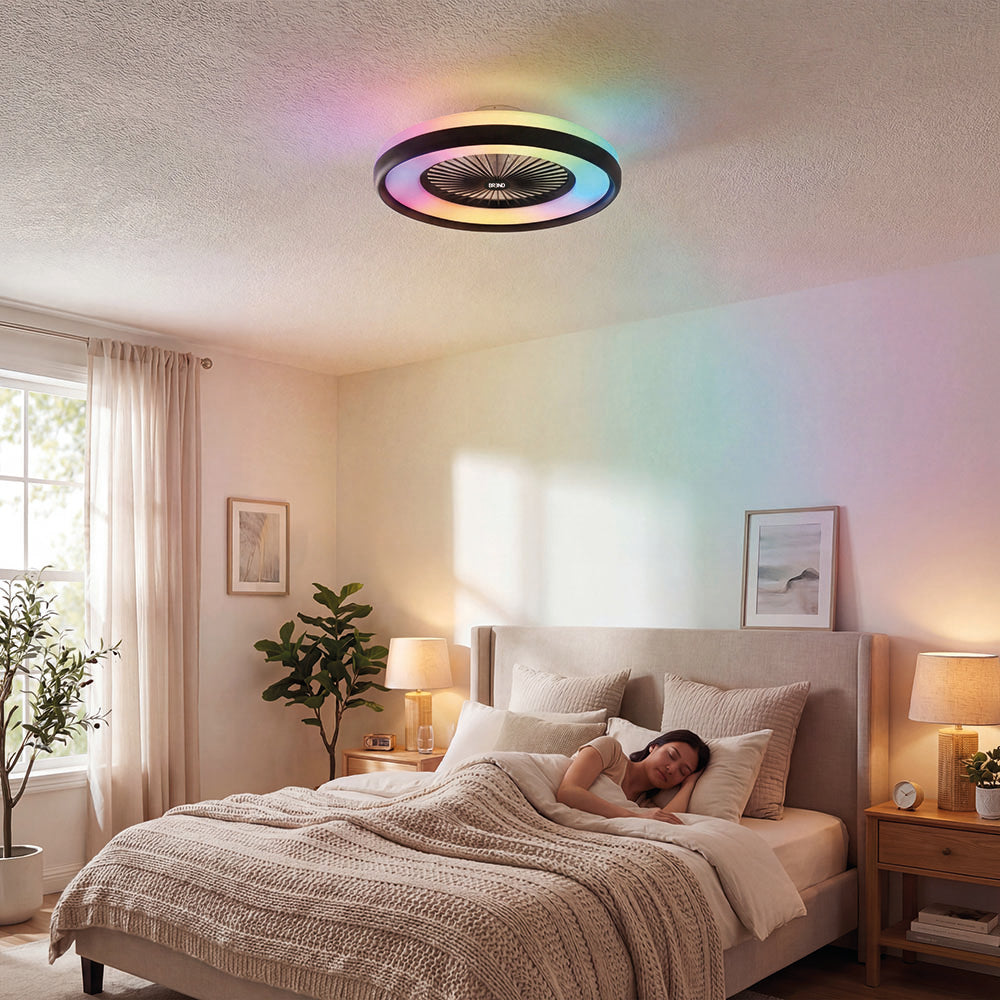Plafondlamp met ventilator geeft gekleurd licht in een slaapkamer waar een vrouw slaapt