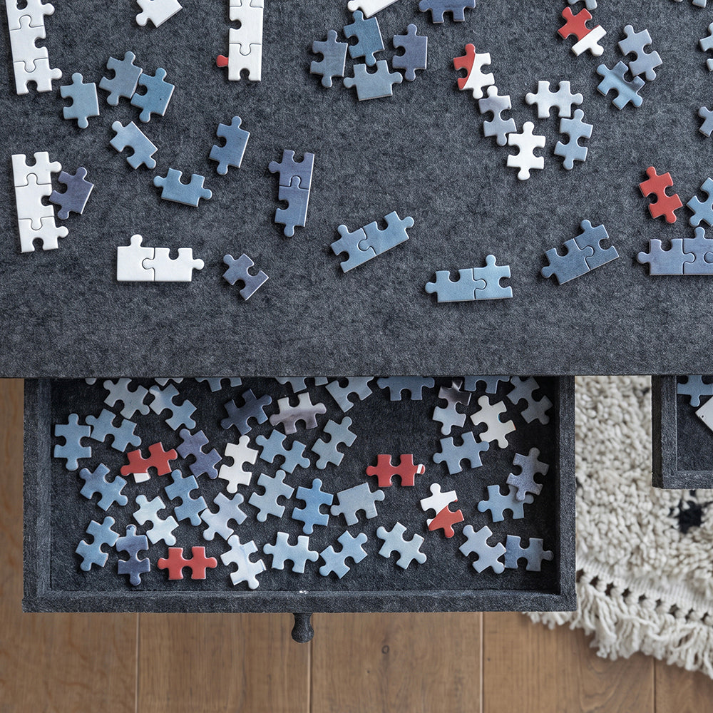 Close-up van een uitgeschoven lade van de grote vilten puzzelplaat met puzzelstukjes