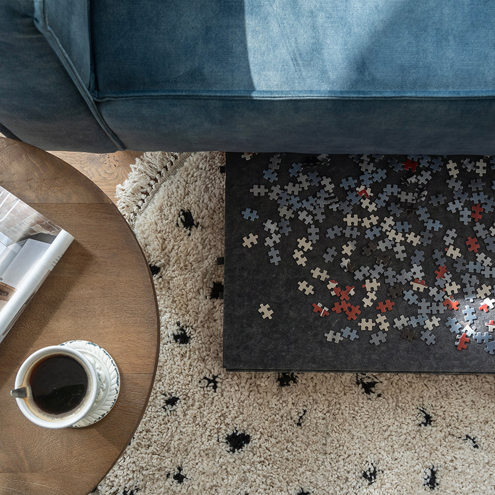 Grote vilten puzzelplaat met puzzelstukjes deels onder de bank geschoven