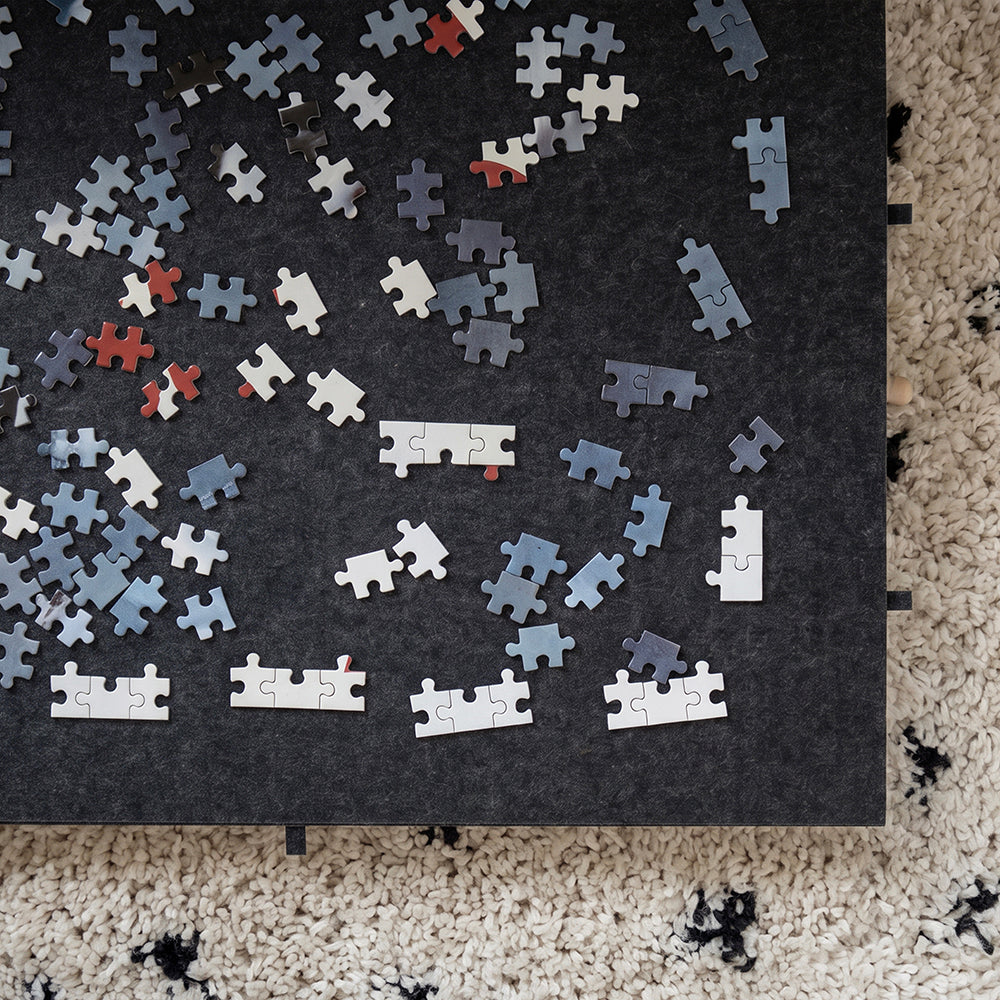 Bovenaanzicht van puzzelstukjes op het vilt van de grote puzzelplaat