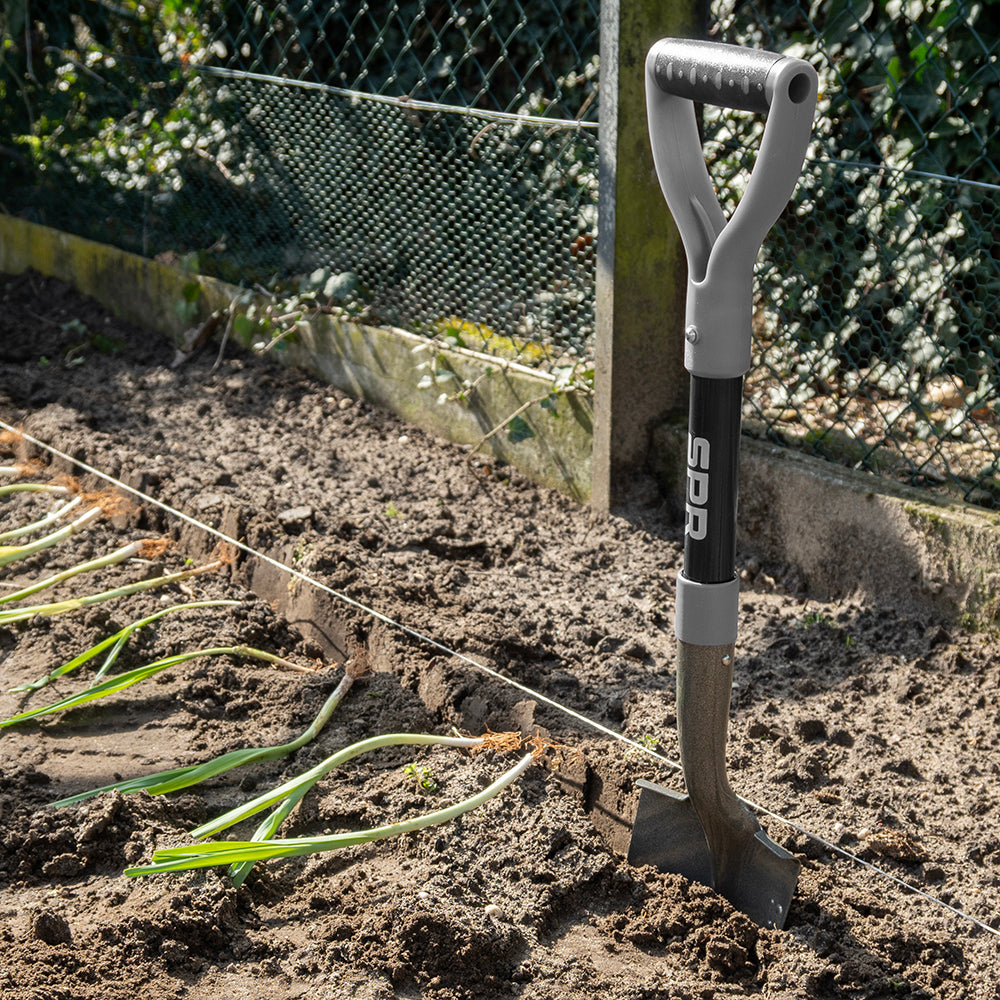 Spade met D-greep staat in de grond van een moestuin