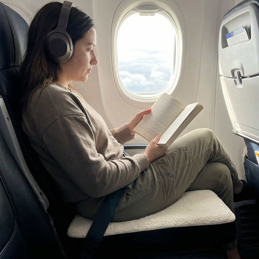 Vrouw leest een boek op het zitkussen in een vliegtuigstoel